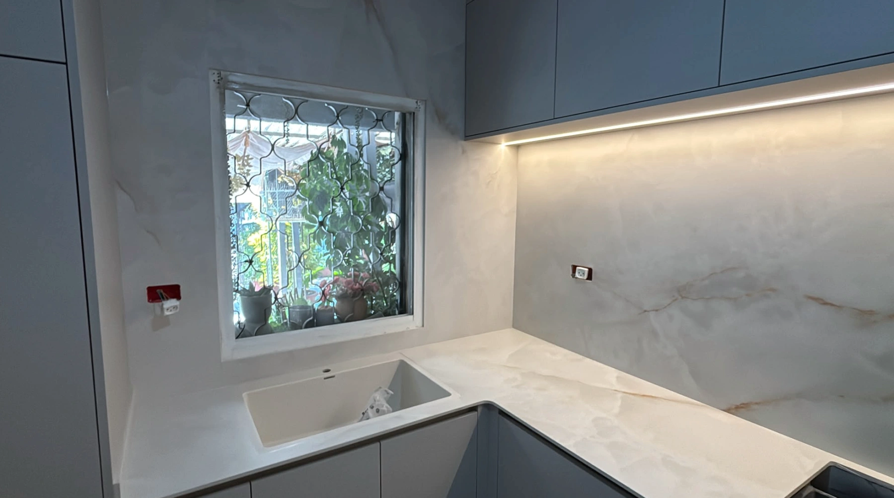 מטבח פינתי בבאר שבע עם Onice White 155 ASCALE, כיור מתחת לחלון וחיפוי קיר תואם