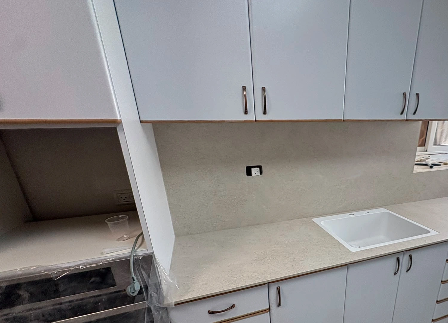 משטח POLOSTONE Sandstone עם כיור לבן באזור חלון במטבח