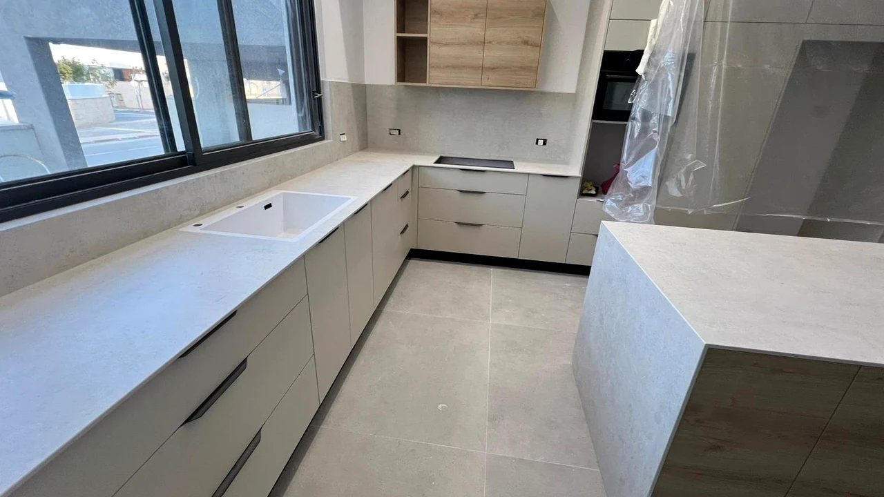 משטח DEKTON LUNAR 12MM ליד חלון עם כיור לבן באופקים