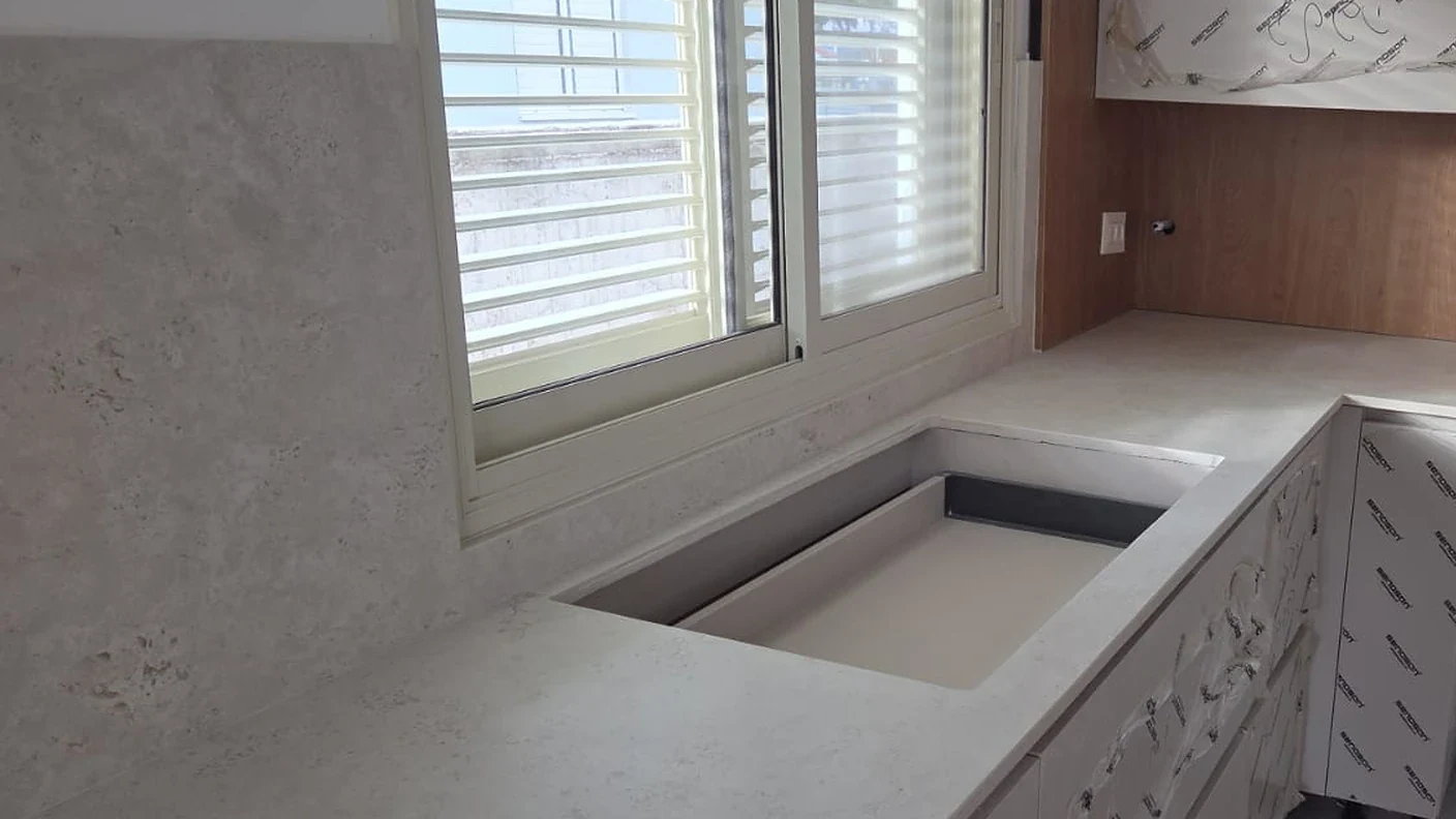 מטבח בקריית מלאכי עם DEKTON Tk05 Sabbia 12MM, כיור מתחת לחלון ונישה בגוון עץ